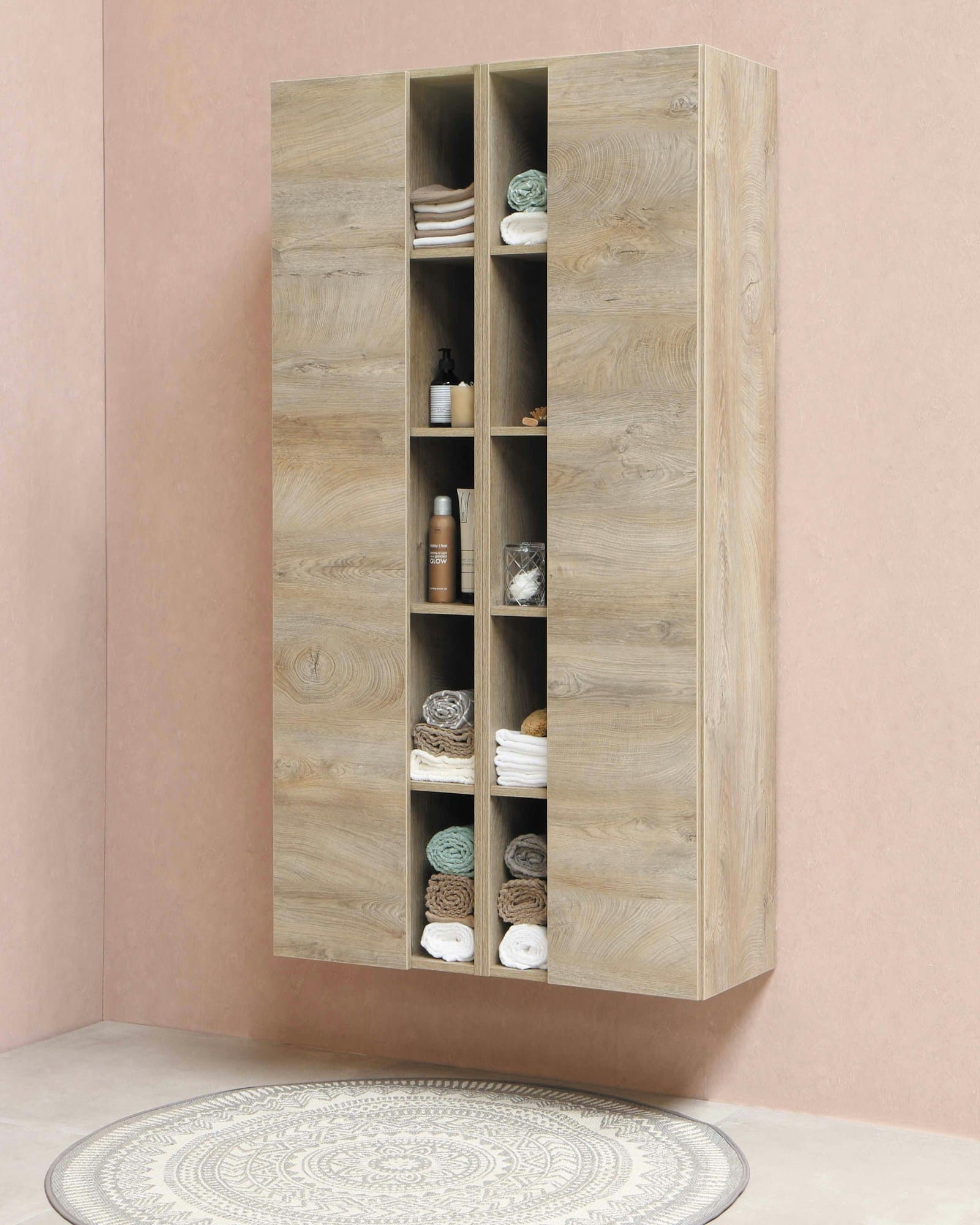A built-in storage unit in pale timber with open compartments and folded linen